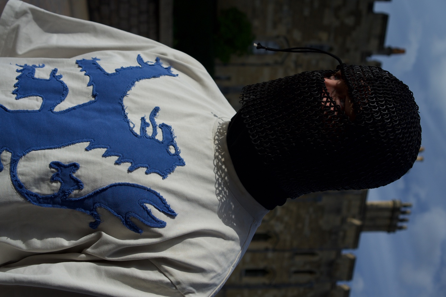 A masked knight in chainmail standing in a castle courtyard